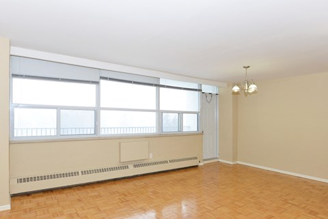 an empty living room with large windows and a wood floor